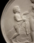 closeup photo with black background of plaster cast relief sculpture of child giving flowers to a mostly nude female figure