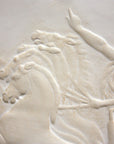 closeup photo of plaster cast relief sculpture of nude male figure in horse-drawn chariot flying