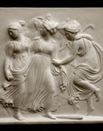 Photo with black background of plaster cast sculpture relief of females dancing