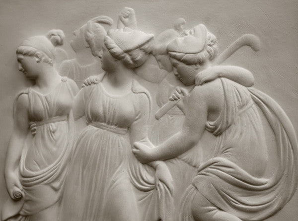 Photo with black background of plaster cast sculpture relief of females dancing