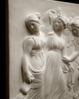 Photo with black background of plaster cast sculpture relief of females dancing