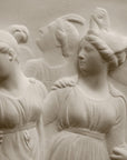 Photo with black background of plaster cast sculpture relief of females dancing