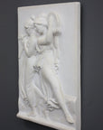 Photo with black background of plaster cast sculpture relief of females playing instruments