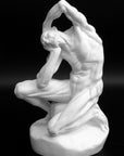 Photo of plaster cast sculpture of flayed man kneeling with hands on head on black background