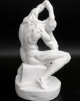 Photo of plaster cast sculpture of flayed man kneeling with hands on head on black background