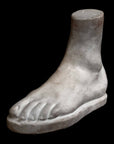 Photo of plaster cast male foot sculpture on a black background