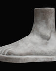 Photo of plaster cast male foot sculpture on a black background