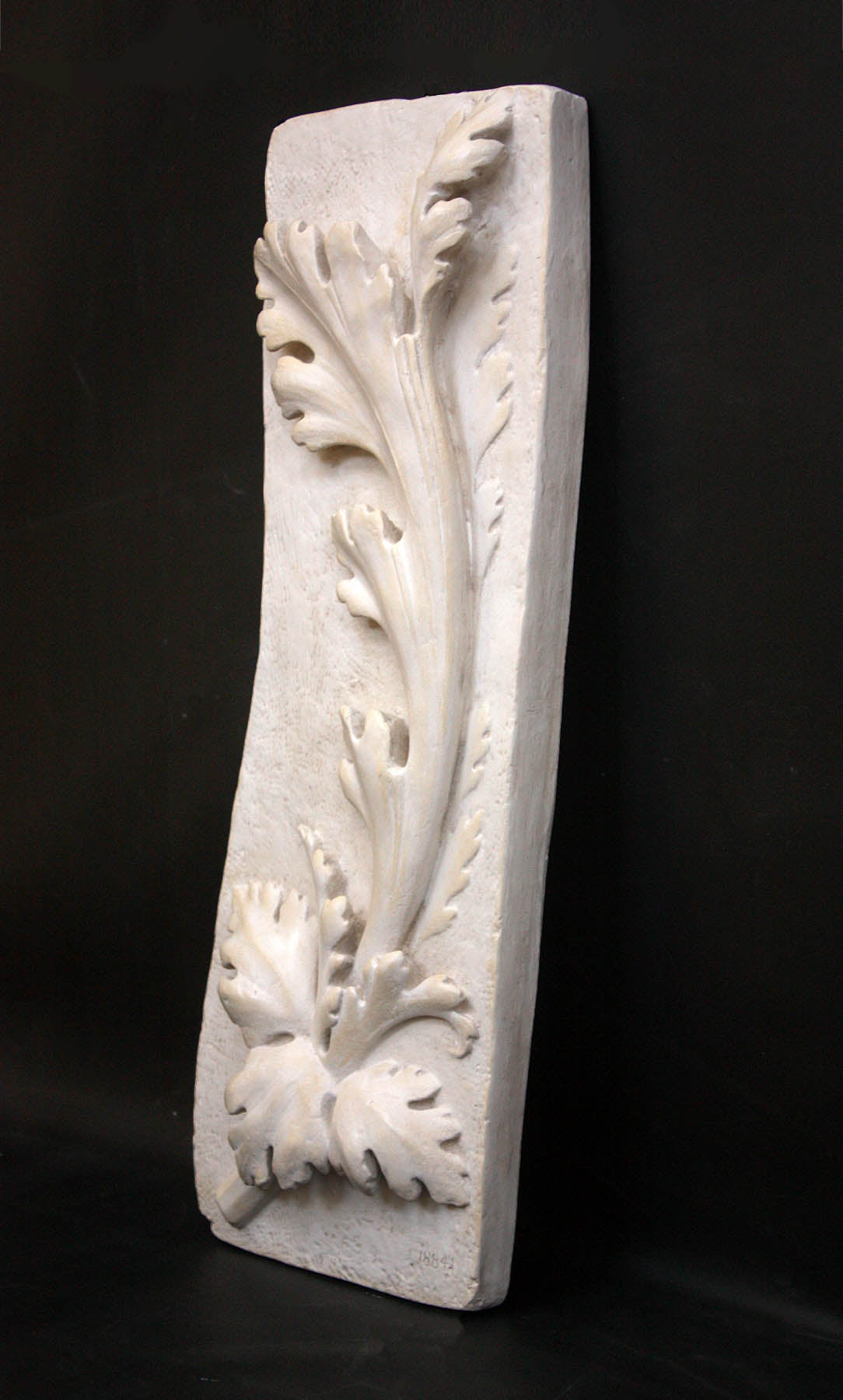 photo of off-white plaster cast relief sculpture of acanthus leaf against black background