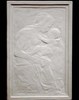 photo of plaster cast sculpture relief of the Madonna holding baby Jesus on her lap on black background