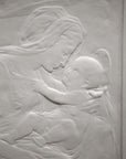 photo detail of plaster cast sculpture relief of the Madonna holding baby Jesus on her lap on black background