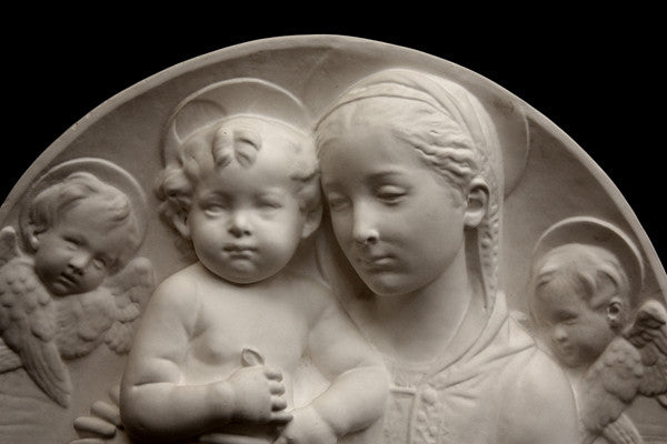 photo of plaster cast sculpture relief of the Madonna holding baby Jesus and angels in the background on a black background