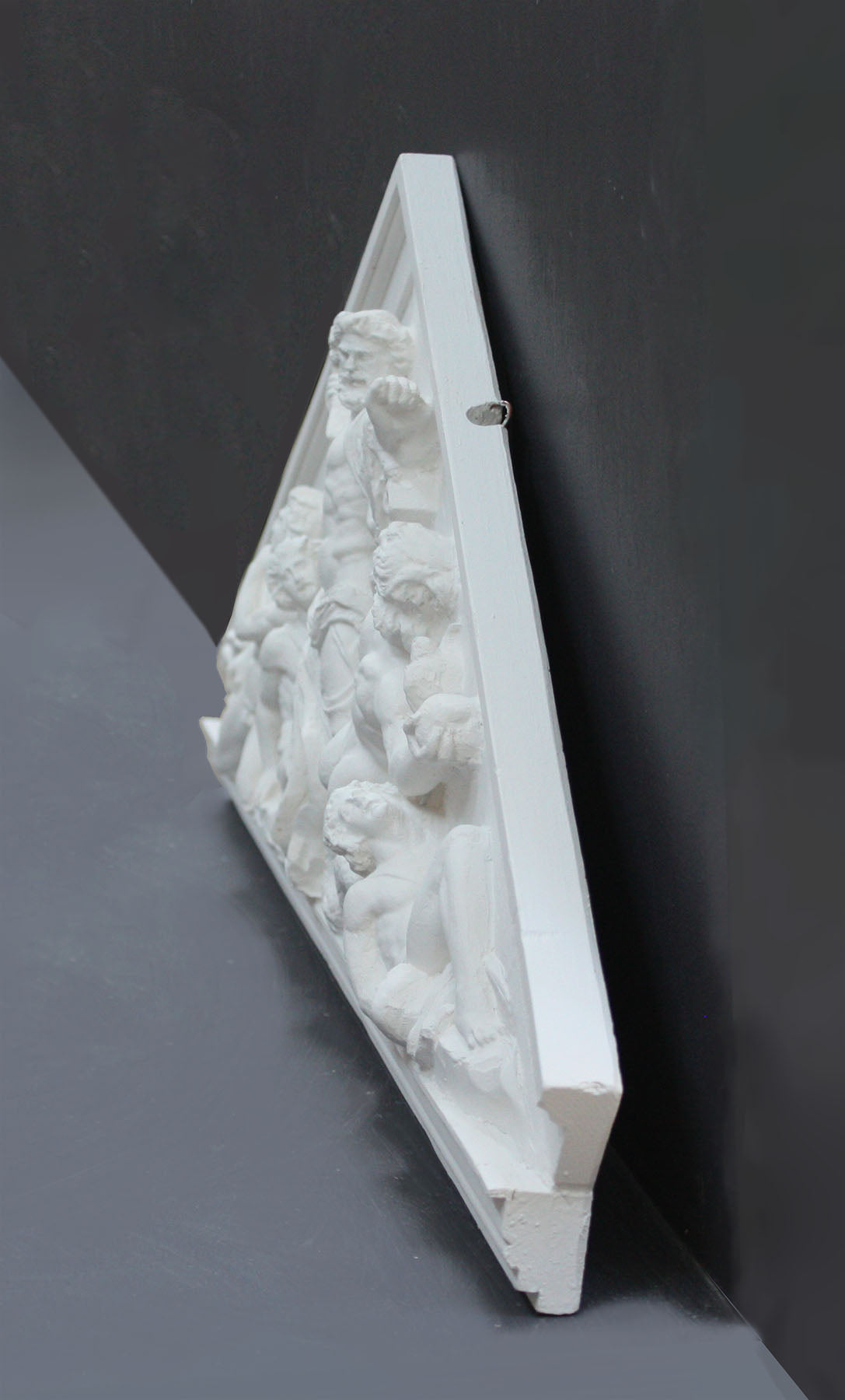 photo of white triangular plaster cast sculpture relief of the god Zeus in the center and the Giants around him on a gray background