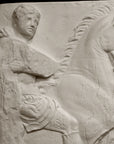 closeup photo of off-white plaster cast relief sculpture of three men on horseback from Parthenon against black background