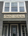 photo of plaster cast relief sculptures of men on horses above doorway on facade of gray house