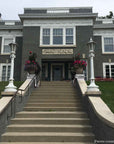 photo of plaster cast relief sculptures of men on horses above doorway on facade of gray house at the top of long staircase