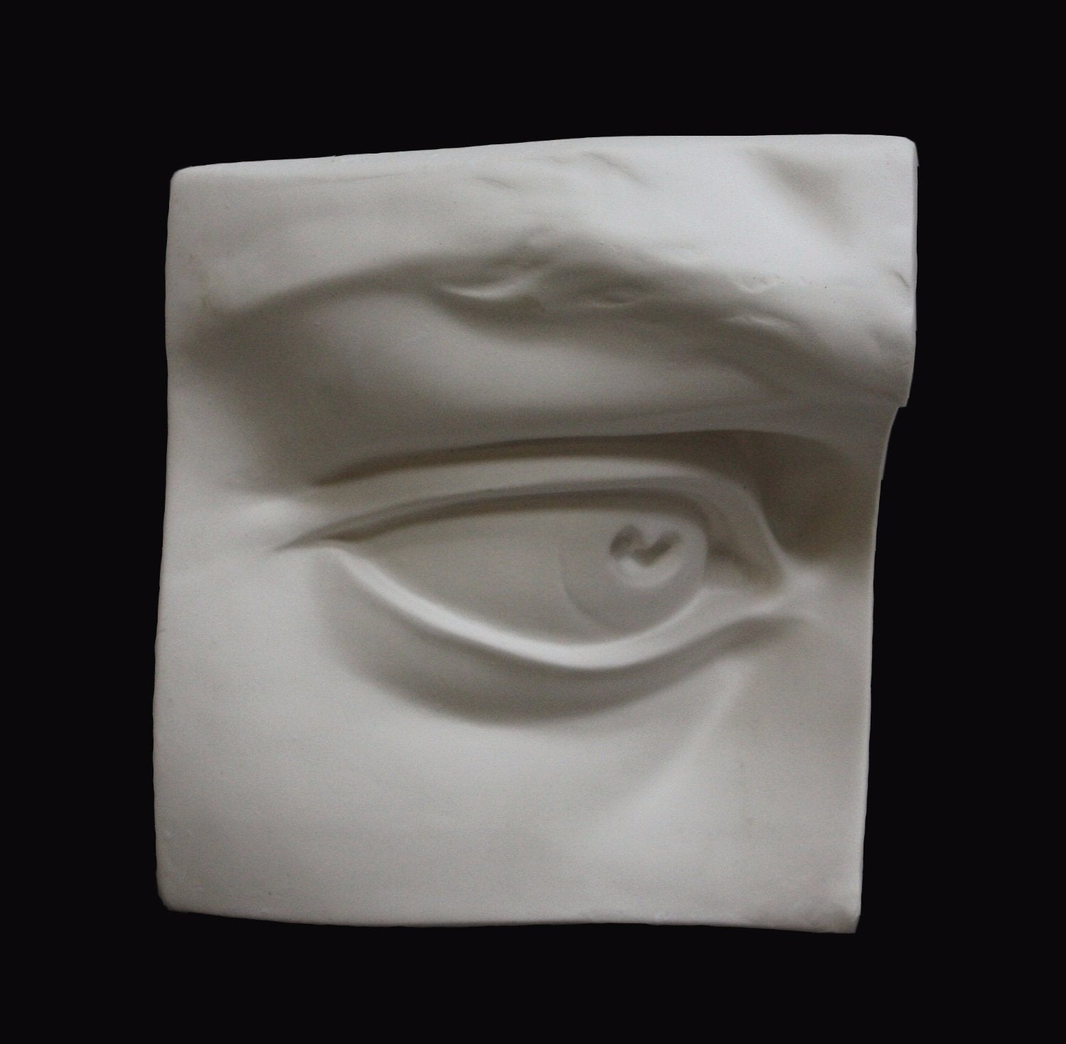 Photo of plaster cast sculpture of right eye on panel from Michelangelo's David statue on a black background