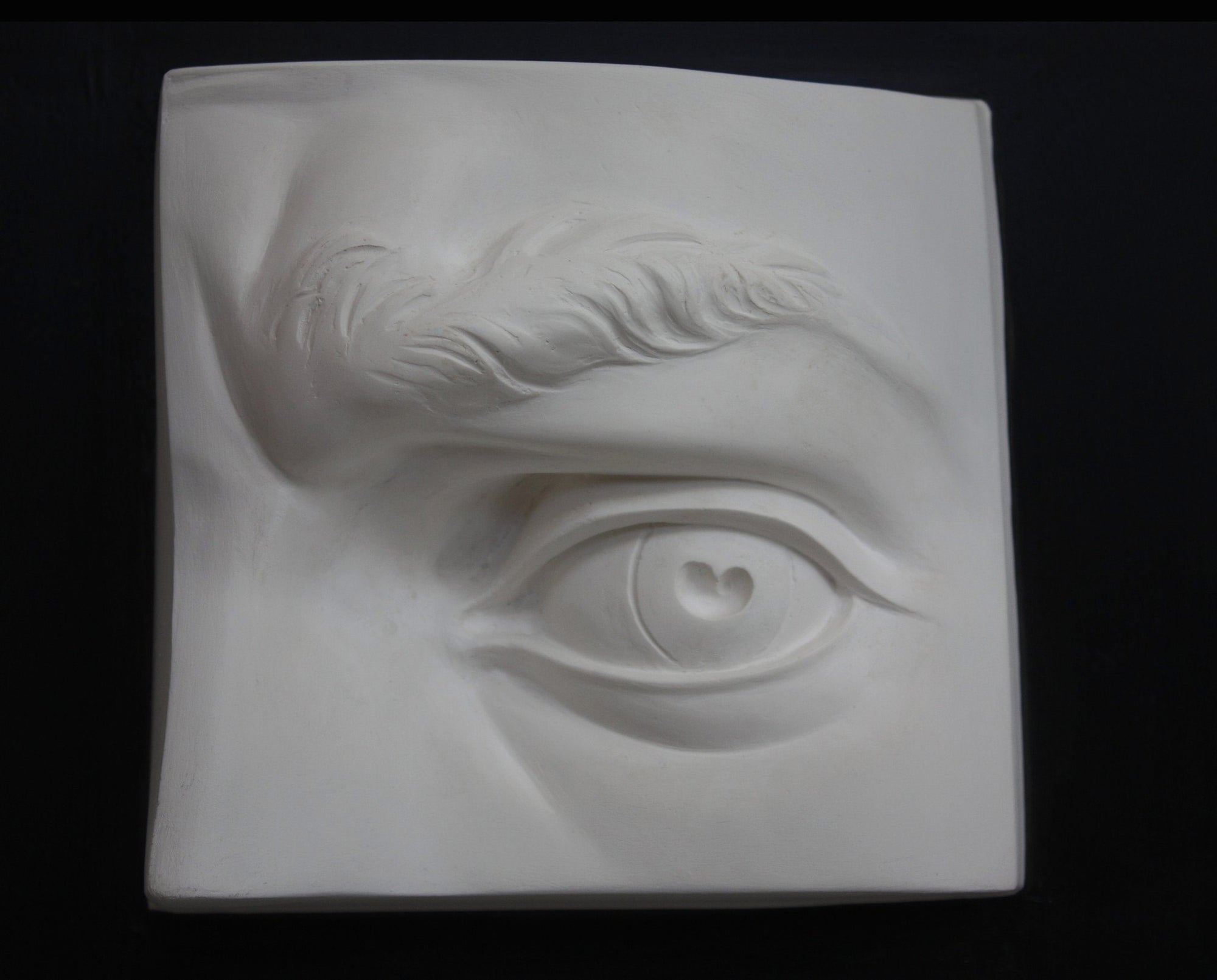 Photo of plaster cast sculpture of portion of face with left eye  from Michelangelo&#39;s David statue on a black background