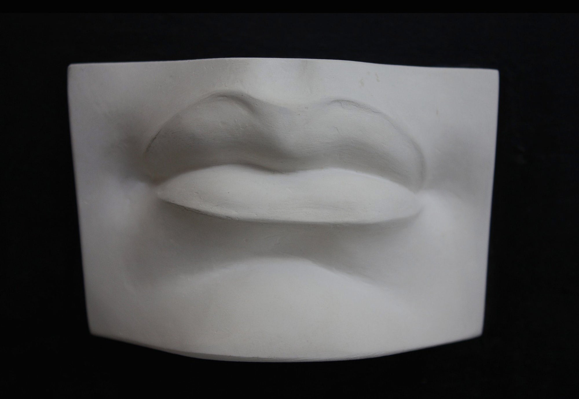 Photo of plaster cast sculpture of mouth from Michelangelo&#39;s David statue on a black background