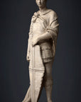 photo of plaster cast sculpture of male figure, namely Saint George, standing in armor and resting shield in front, on dark gray background