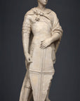 photo of plaster cast sculpture of male figure, namely Saint George, standing in armor and resting shield in front, on dark gray background