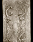 photo with black background of yellowed plaster cast relief sculpture of two robed female figures touching tree branches above their heads