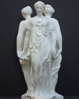 photo of white plaster cast sculpture of three robed females standing in a circle with their backs to each other against a gray background