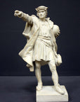 photo of plaster cast sculpture of standing man, namely Christopher Columbus, in robes and hat, pointing with right hand and holding a globe in his left arm against gray background