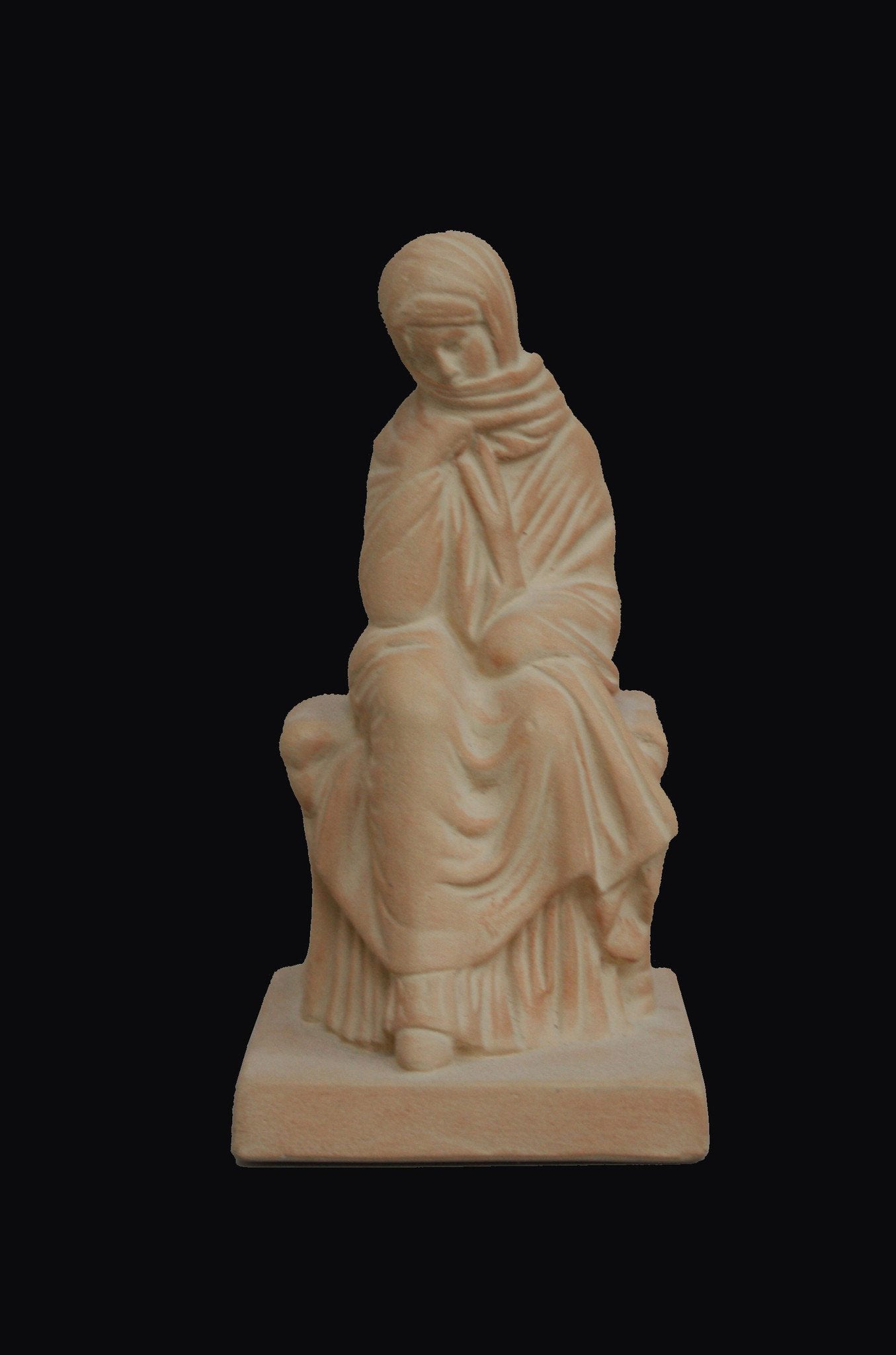 photo with a black background of a plaster cast sculpture of a seated female figurine painted terra cotta