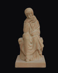 photo with a black background of a plaster cast sculpture of a seated female figurine painted terra cotta