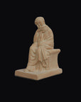 photo with a black background of a plaster cast sculpture of a seated female figurine painted terra cotta