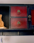 Photo of a plaster cast of a seated female figurine painted terra cotta on a small Chinese cabinet hanging on the wall