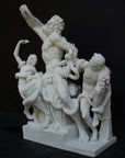 photo with black background of plaster cast sculpture of partially nude male figure, namely Laocoon, and two nude young men being attacked by serpents which twist in and out of the three figures