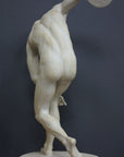 Photo with black background of plaster cast of nude male athlete readying to throw a discus