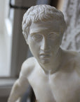 Photo closeup of face of plaster cast of nude male athlete readying to throw a discus