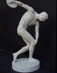 Photo with black background of plaster cast of nude male athlete readying to throw a discus