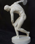 Photo with black background of plaster cast of nude male athlete readying to throw a discus