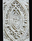 photo of white plaster cast of architectural ornament with geometric lines and leaf patterns against black background