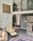 photo of plaster casts of an architectural ornament in terracotta color in a row on off-white wall in room with tan chairs and couch, rug, stone fireplace, and plants and green wall in background