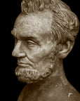 photo with black background of yellowed plaster cast bust sculpture of man with beard, namely Lincoln